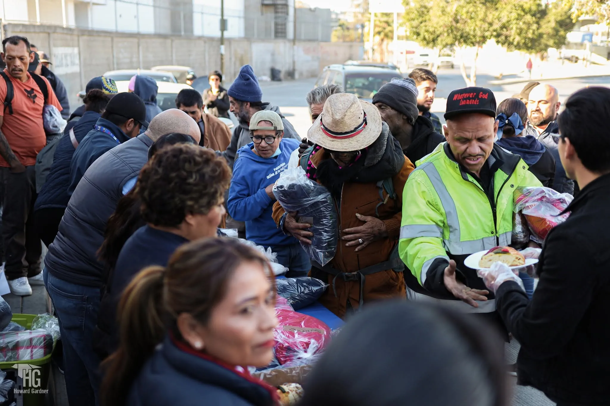 Personas reunidas recibiendo calzado y alimento durante la entrega