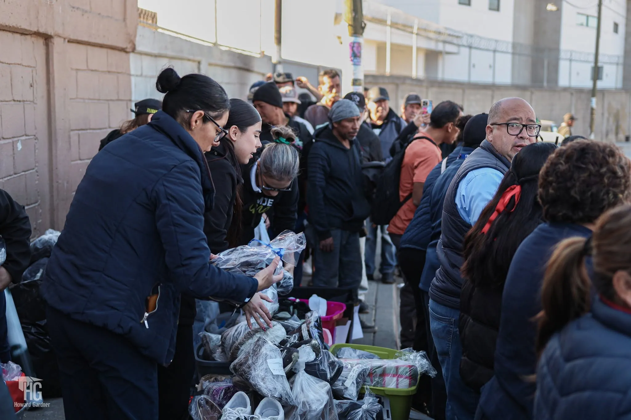 Muchas personas reunidas recibiendo calzado y ropa durante la entrega