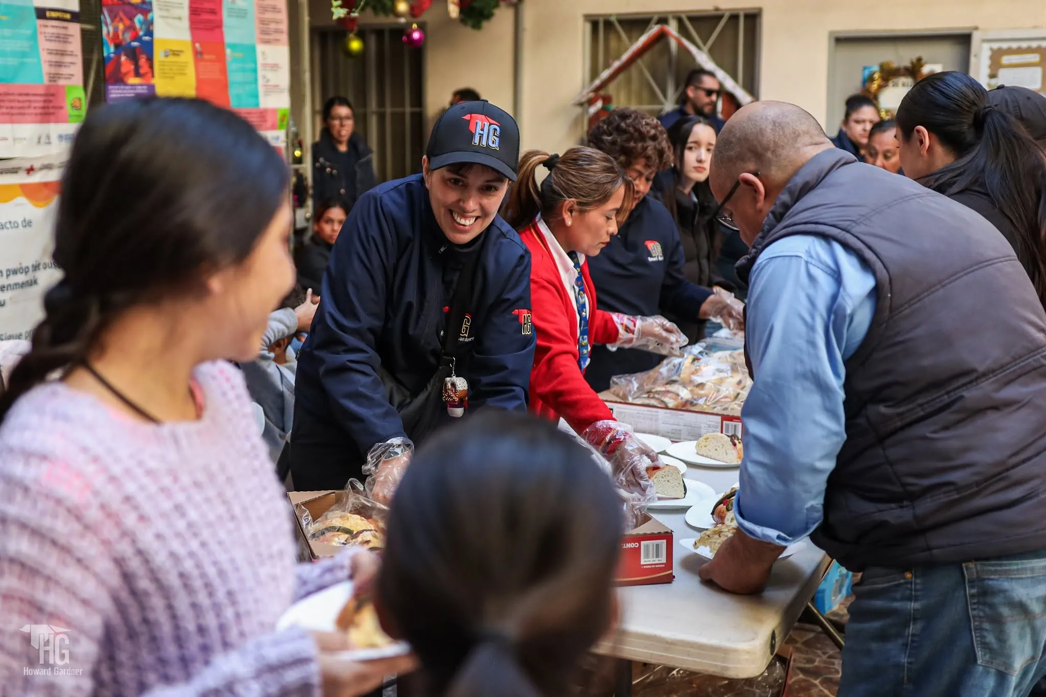 Una niña sonríe frente a la mesa donde voluntarios sirven alimentos