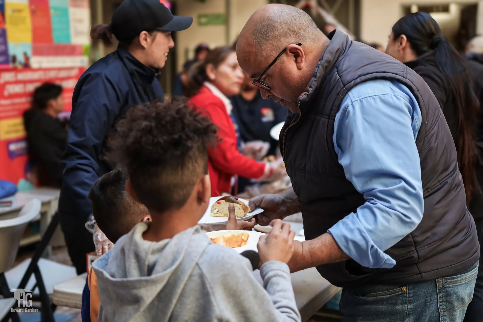 Un voluntario sirve alimento a un niño durante la jornada